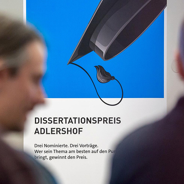 Ein Aufsteller mit der Aufschrift Dissertationspreis Adlershof. Zu sehen ist ein Abolventenhut.