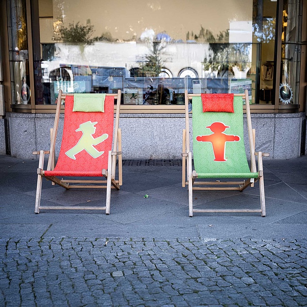 Ampelmännchen-Liegestühle Zwei Liegestühle vor einem Geschäft. Links ein roter Liegestuhl mit grünem Ampelmännchen und rechts ein grüner mit rotem Ampelmännchen.