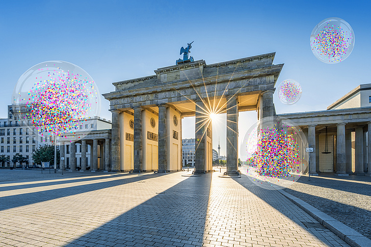 Keyvisual Berlin University Alliance Ein Bild vom Brandenburger Tor, im Hintergrund blauer Himmel und Sonnenstrahlen, die zwischen den Säulen hervorscheinen. Im Bild sind auch vier transparente Blasen mit Konfetti zu sehen.
