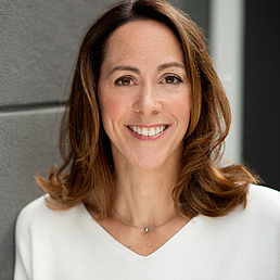 Gisela Rühl Gisela Rühl lächelt in die Kamera und trägt eine weiße Bluse und eine Kette mit einem Edelstein