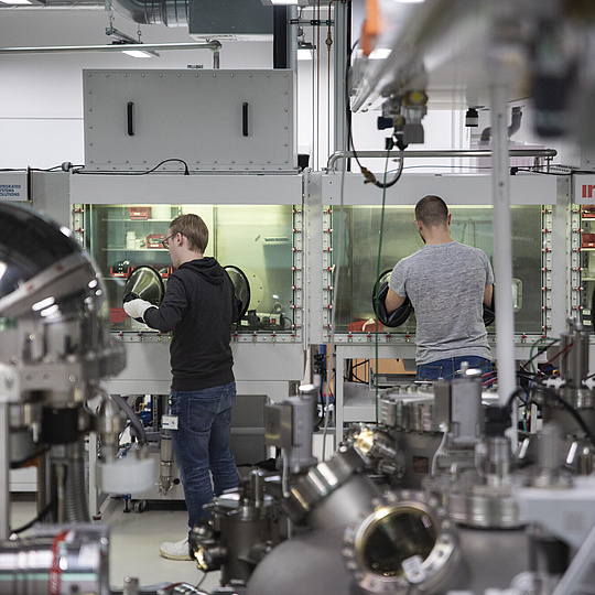 Mitarbeiter im Forschungslabor des Center of Science of Materials Berlin (CSMB) Zwei Männer arbeiten in einem Raum voller technischer Versuchsgeräte des CSMB der HU.