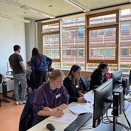 Teilnehmerinnen des Girls' Day Mehrere Personen sitzen an Computern in einem Klassenzimmer mit großen Fenstern.