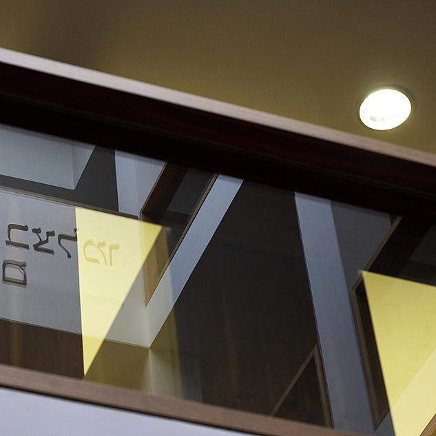 Theologisches Institut am Campus Mitte Das Bild zeigt eine mit Glas verzierte Holzwand, in der sich Buchstaben des hebräischen Alphabets spiegeln.