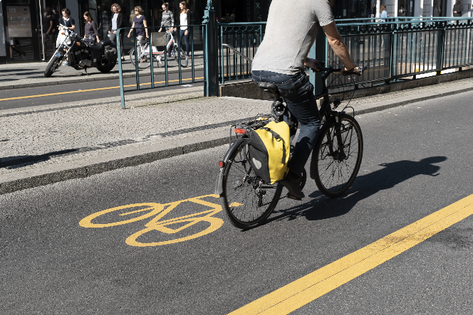 Ein Fahrradweg mit einem gelben Fahrradsymbol. Eine Person fährt mit dem Fahrrad darauf.